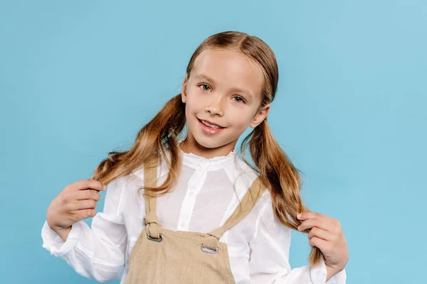 Sonriente Lindo Niño Mirando Cámara Tocando Pelo Aislado Azul — Foto de Stock