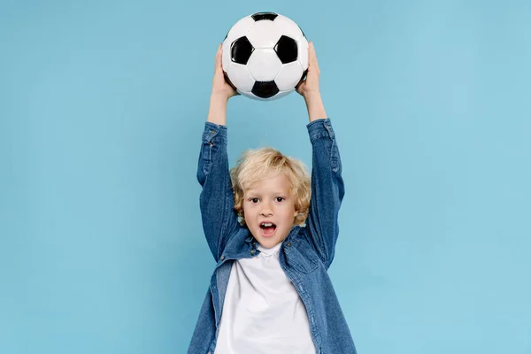 cute kid holding football and screaming isolated on blue 