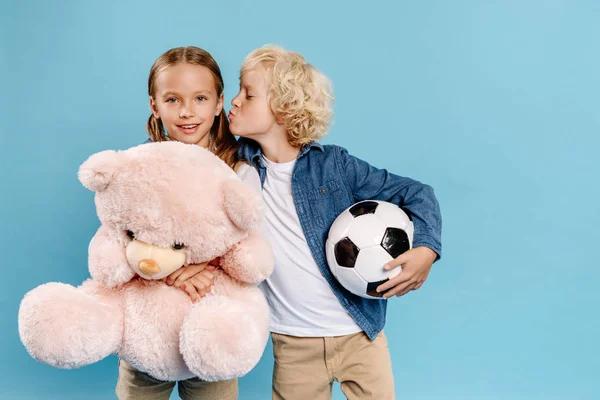 男孩与足球亲吻的朋友与泰迪熊隔离在蓝色 — 图库照片