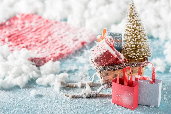 Hasır kızakta hediye kutularının ve Noel ağacının seçici odak noktası, alışveriş torbaları. 