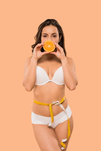 속옷으로 얼굴을 여자가 베이지 색으로 고립된 오렌지 반쪽으로 얼굴을 가리고 — 스톡 사진