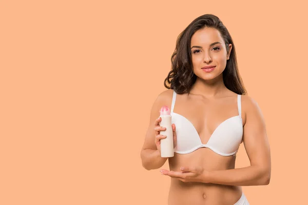 attractive woman holding deodorant spray isolated on beige