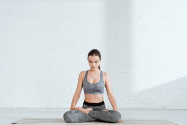 young woman in sportswear practicing yoga in lotus pose clipart