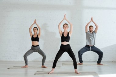 Genç erkek ve kadın tanrıça pozu vererek yoga yapıyorlar.
