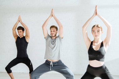 Genç erkek ve kadın tanrıça pozu vererek yoga yapıyorlar.