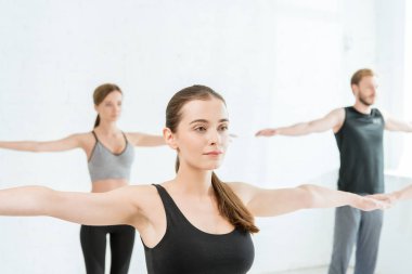 Dağda yoga yapan genç kadın ve erkek kol pozu veriyor.