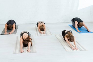 Beş genç çocuk uzun pozlarda yoga yapıyor.