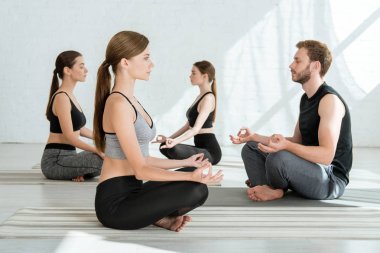 Yarı nilüfer pozunda yoga yapan gençlerin yan görünüşü