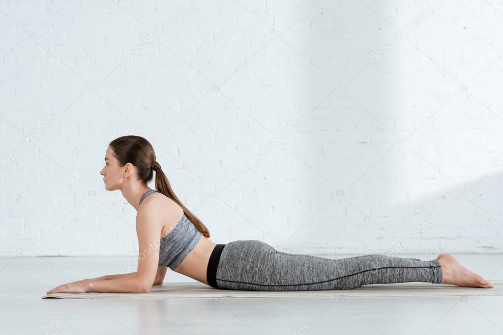 side view of young woman in sportswear practicing yoga in sphinx pose