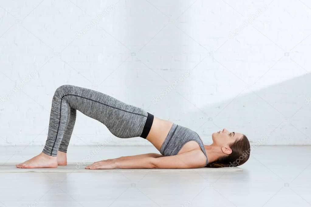young woman in sportswear practicing yoga in upward plank pose