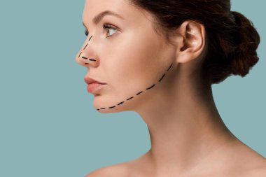 young naked woman with marked lines on face looking away isolated on blue  clipart