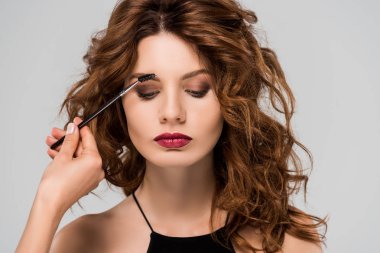 cropped view of makeup artist styling eyebrows of beautiful woman isolated on grey  clipart