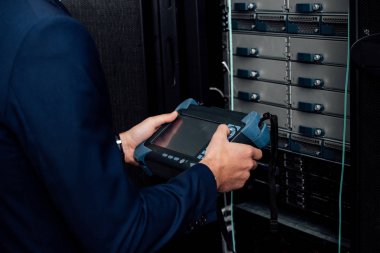 cropped view of man holding reflectometer in server room  clipart