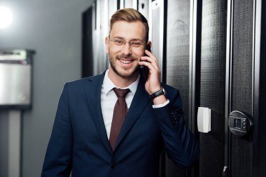 Gözlüklü neşeli iş adamı sunucu odasında akıllı telefondan konuşuyor. 