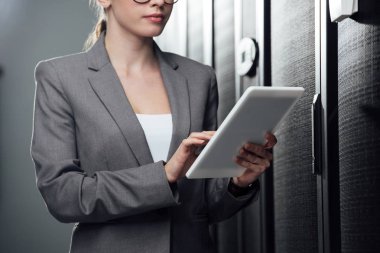 cropped view of businesswoman holding digital tablet in server room  clipart