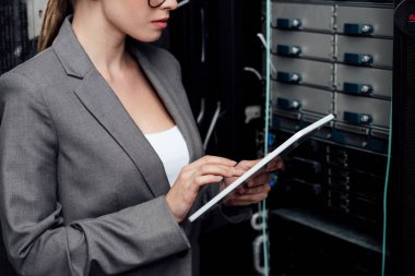 cropped view of businesswoman using digital tablet near server rack  clipart