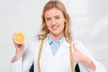 Sırıtkan diyetisyen, elinde bant ile turuncu kesilmiş halde klinikteki gibi gösteriyor. 