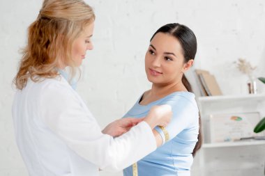 Klinikte ölçüm bandıyla hastanın elini ölçen çekici beslenme uzmanı. 