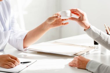 Dermatoloğun klinikteki hastaya kozmetik kremi verirken çekilmiş görüntüsü.
