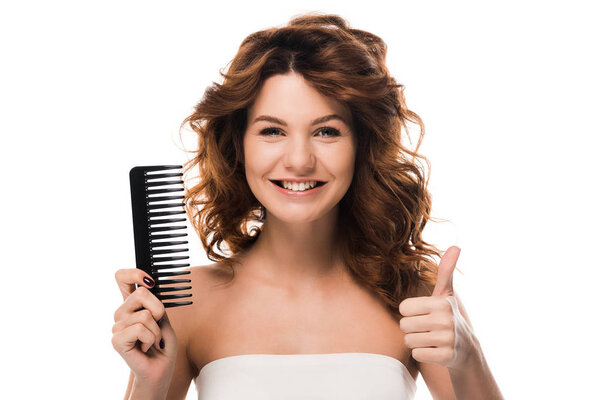 happy girl with curly hair holding hair brush and showing thumb up isolated on white 