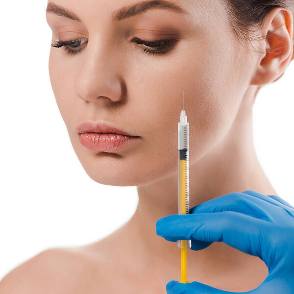 cropped view of plastic surgeon in blue latex glove holding syringe near attractive naked woman isolated on white 