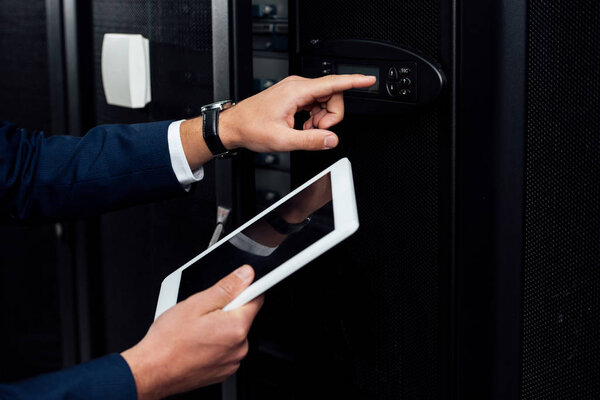 обрезанный вид человека, держащего цифровой планшет, указывая пальцем на цифровую панель
 