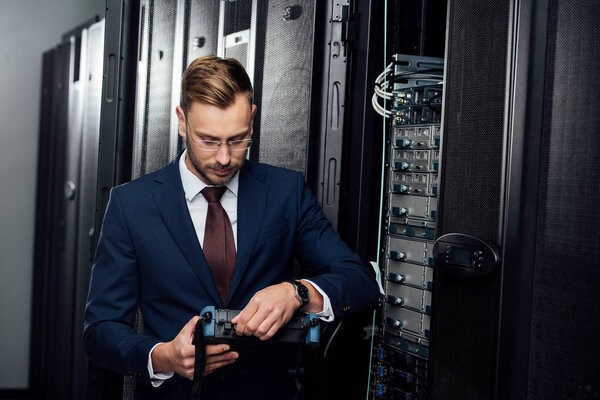 bearded businessman holding reflectometer in server room 