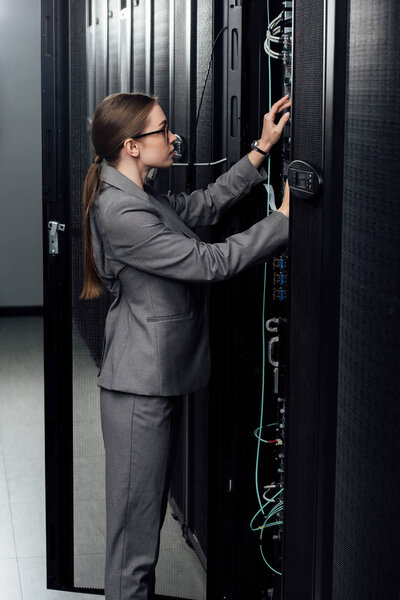 attractive businesswoman in glasses looking at server rack in data center 