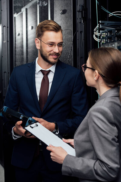 selective focus of handsome businessman holding reflectometer near businesswoman in data center 