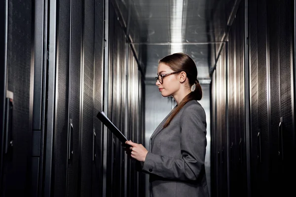 データセンターでクリップボードを保持しているメガネのビジネス女性の側面図 — ストック写真