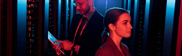 panoramic shot of attractive businesswoman near businessman with digital tablet in data center 