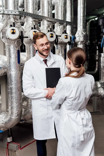 Fröhlicher Ingenieur Schaut Mitarbeiter Während Der Nähe Der Luftkompressoranlage Steht — Stockfoto