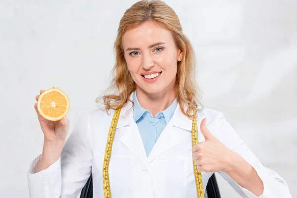Nutricionista Sonriente Con Cinta Métrica Sosteniendo Corte Naranja Mostrando Como —  Fotos de Stock