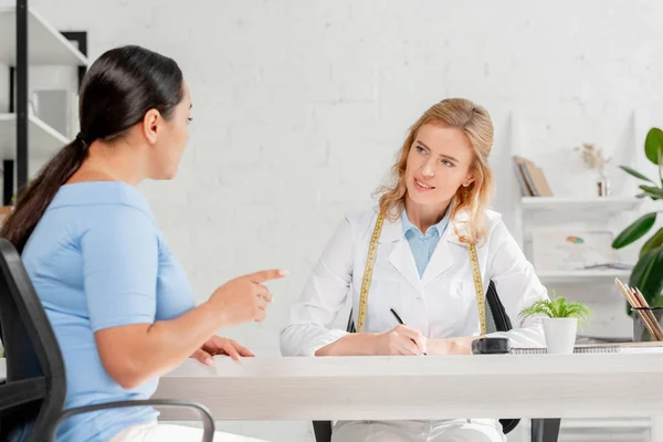 Nutricionista Atraente Sentado Mesa Conversando Com Paciente Clínica — Fotografia de Stock