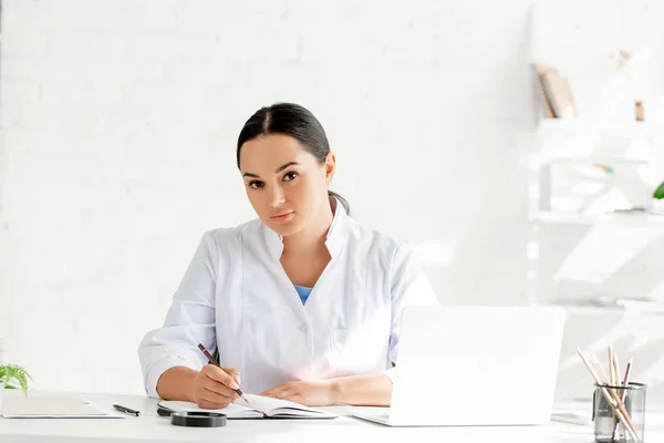 Atractivo Dermatólogo Sentado Mesa Mirando Cámara Clínica — Foto de Stock