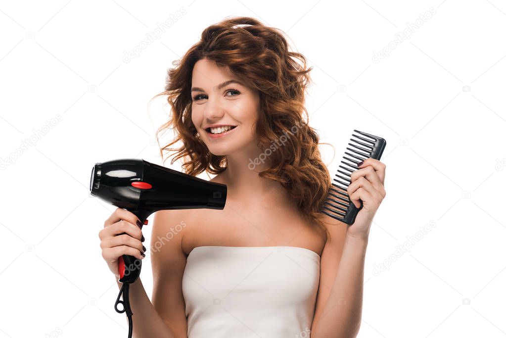 happy curly girl holding hair dryer and hair brush isolated on white 