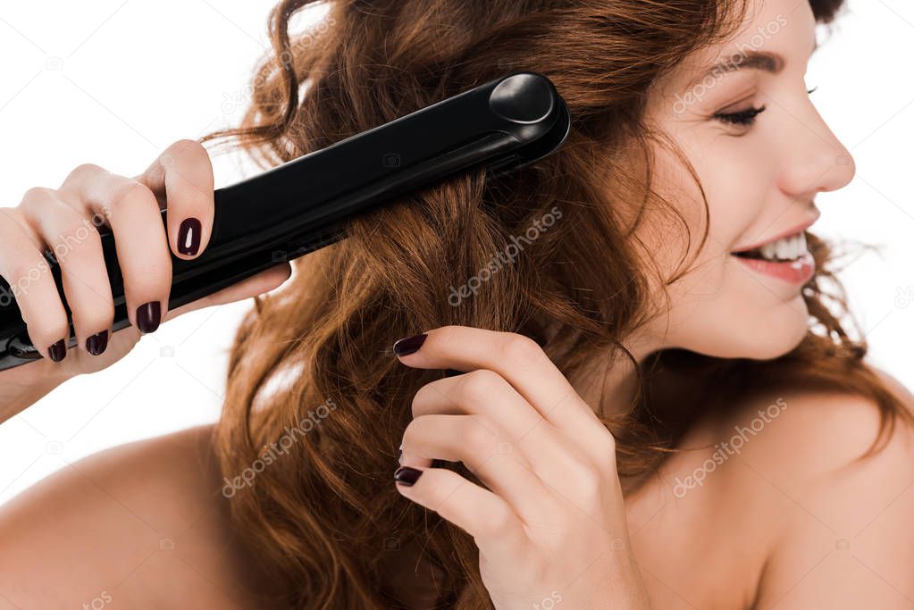 happy curly woman using hair straightener isolated on white  