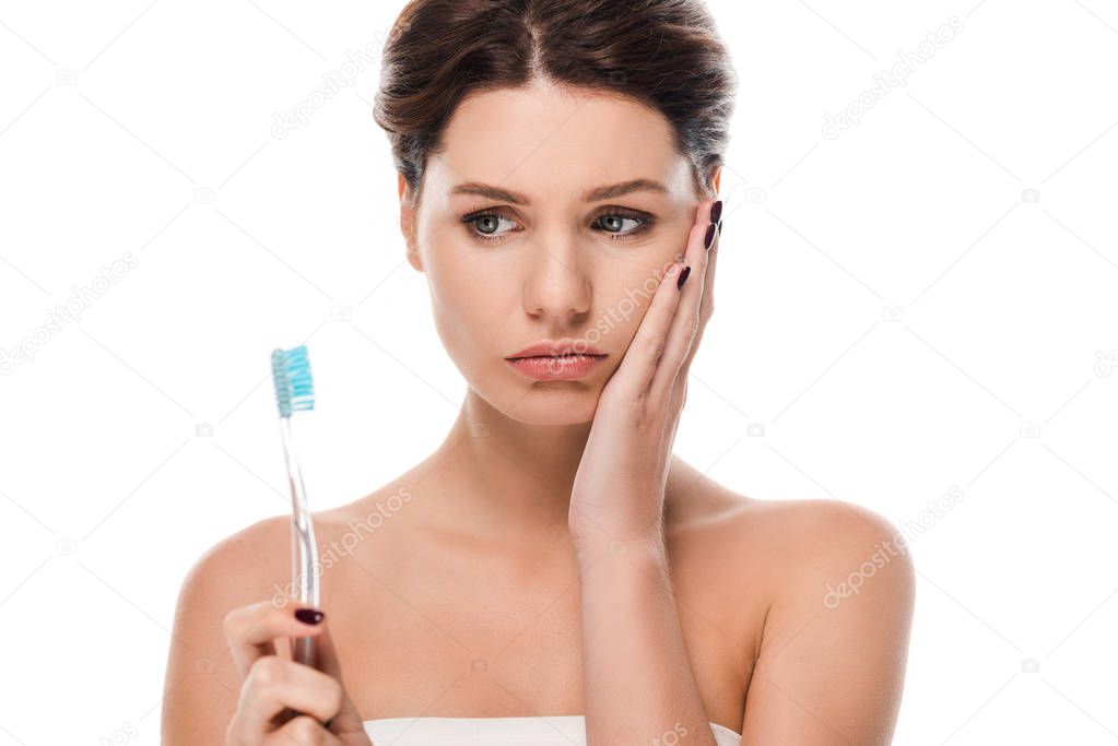 sad young woman touching face while holding toothbrush isolated on white 