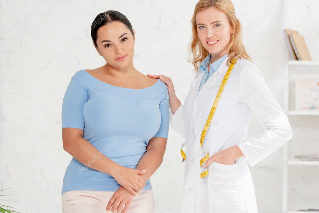 attractive nutritionist and patient looking at camera in clinic 