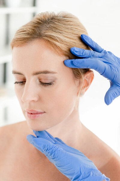 cropped view of dermatologist examining skin of patient in clinic