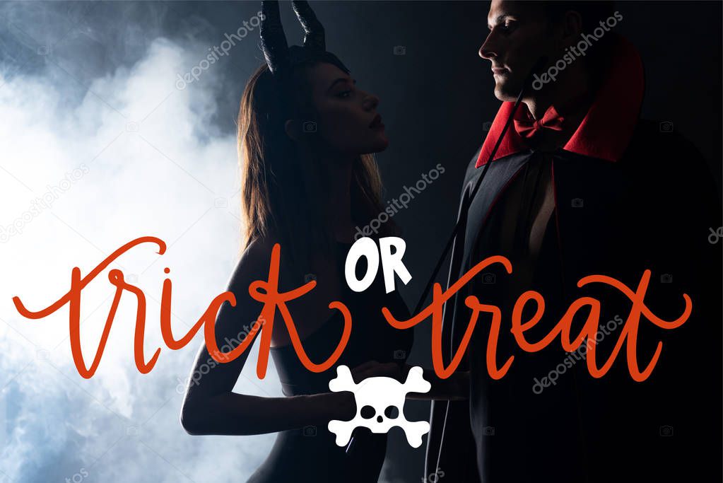 handsome man in cloak looking at girl with horns holding flogging whip on black background with smoke and trick or treat illustration