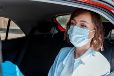 woman in medical mask and gloves sitting in taxi during covid-19 pandemic clipart