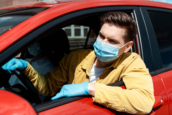 man in medical mask and protective gloves driving taxi during coronavirus pandemic