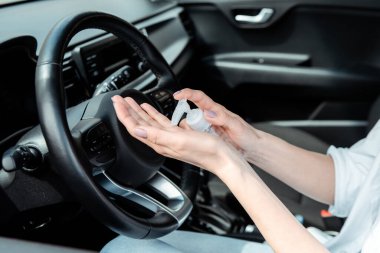 Koronavirüs salgını sırasında arabada antiseptik kullanan kadın görüntüsü.