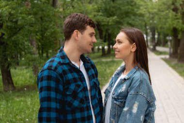 side view of happy couple looking at each other in park  clipart