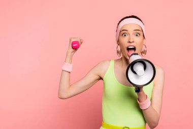 emotional sportswoman holding loudspeaker and dumbbell while screaming on pink  clipart