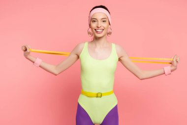 Mutlu sporcu kadın pembe bantla egzersiz yapıyor. 