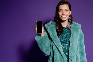 Mor ekranda boş ekranı olan akıllı telefonu tutan mutlu kadın. 