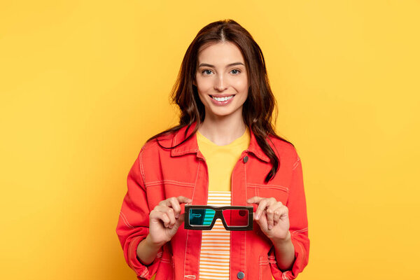 happy young woman holding 3d glasses on yellow 
