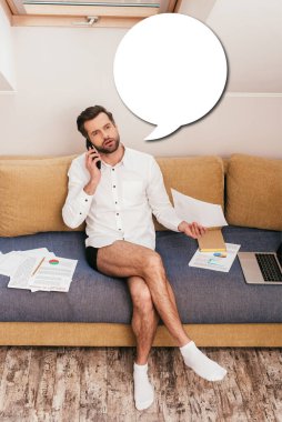 Gömlek ve külot giyen yakışıklı, akıllı telefondan konuşan, kanepede doküman tutan, boş konuşma balonu çizimi